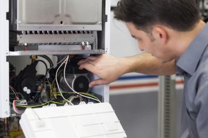 Technician inspecting internal components of an HVAC system during maintenance service.
